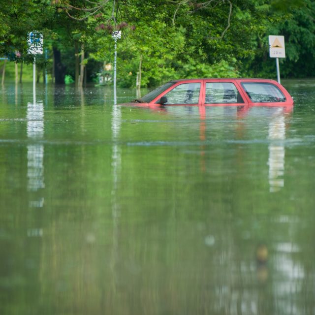 A car being partially underwater in a flooded street